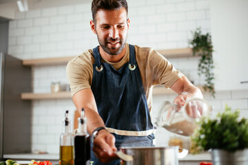 Happy man in kitchen. Young man preparing delicious food