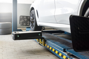 Car on wheel alignment station with sensor and laser reflector on wheel hub to check in workshop.