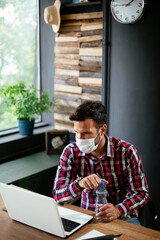 Young businessman with a mask working in his office on laptop. COVID - 19 virus protection..