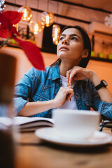 Inspired beautiful young woman looking away sitting at cafeteria