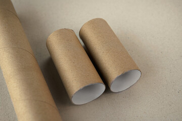 Group of Toilet paper roles lying down horizontally made of recycled brown paper or cardboard on a similar beige coloured background