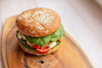 Burger with king prawn, feta cheese and vegetables, on a wooden board