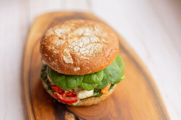 Burger with king prawn, feta cheese and vegetables, on a wooden board