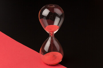 Crystal hourglass on black and red background as a concept of passing time for business term,...