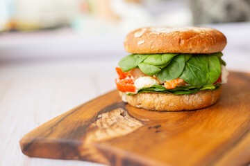 Burger with king prawn, feta cheese and vegetables, on a wooden board