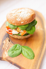 Burger with king prawn, feta cheese and vegetables, on a wooden board