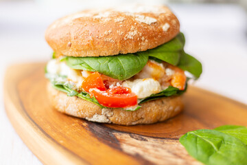 Burger with king prawn, feta cheese and vegetables, on a wooden board