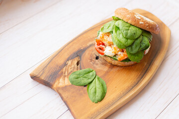 Burger with king prawn, feta cheese and vegetables, on a wooden board