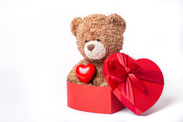 teddy bear sitting in a heart shaped box isolated on a white background