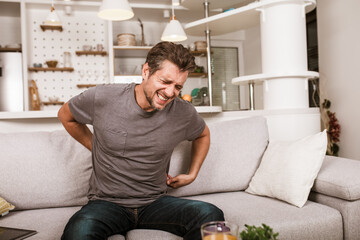 Unhappy man suffering from backache at home