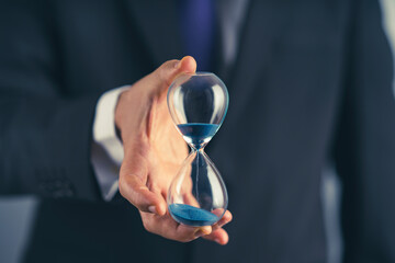 Business man holding hourglass in hand
