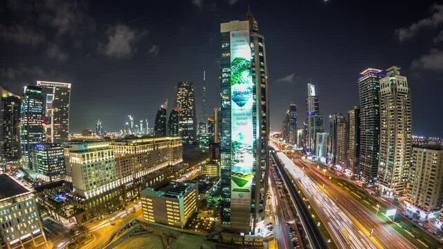 Downtown Dubai towers night timelapse. Aerial view of Sheikh Zayed road with skyscrapers. Traffic on the road and metro line. Blinking lights and trails. Fisheye lens panorama