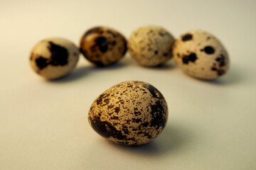 Obraz premium five raw quail eggs lie side by side on a light beige background . healthy eating