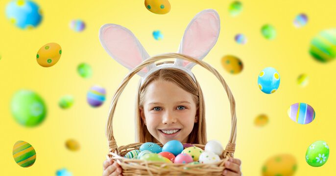easter, holidays and people concept - happy smiling girl wearing bunny ears headband with basket of colored eggs over yellow background