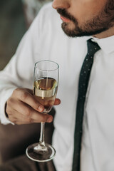 a glass of champagne in the hand of a brutal businessman