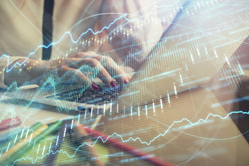 Double exposure of woman hands typing on computer and financial graph hologram drawing. Stock...