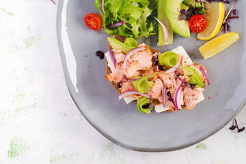 Sandwich with baked salmon. Tapas. Sandwich with salmon, feta cheese, avocado and microgreens. Top view, overhead