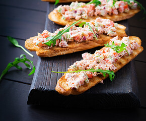 Bruschetta with baked salmon. Tapas. Sandwich with salsa of salmon, feta cheese, avocado, tomatoes  and red onion. Toasts with riyet salmon.