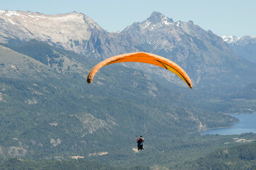 paraglider, instructor and passenger flying over lakes and mountains of bariloche