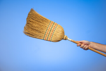 Caucasian male hand holding a braided broom isolated on blue background