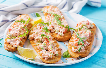 Bruschetta with baked salmon. Tapas. Sandwich with salsa of salmon, feta cheese, avocado, tomatoes  and red onion. Toasts with riyet salmon.