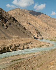 Spiti river flanked by Himalayas under blue sky near Tabo, Himachal Pradesh, India.