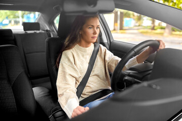 Fototapeta na wymiar safety and people concept - young woman or female driver driving car in city