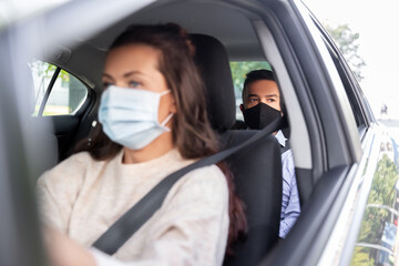 Obraz na płótnie Canvas transportation, health and people concept - female driver driving car with male passenger wearing face protective medical mask for protection from virus disease