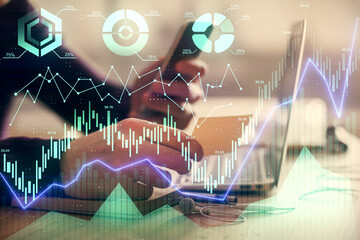 Double exposure of man's hands holding and using a phone and financial graph drawing. Analysis concept.