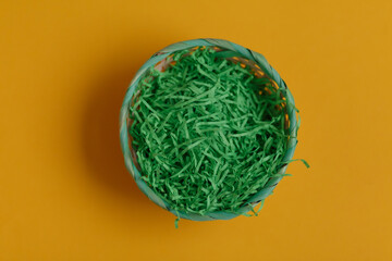 Green basket for easter eggs on a yellow background