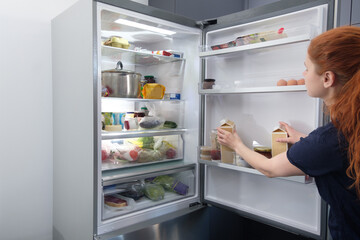 Woman opening drawer of refrigerator with vegetables, closeup