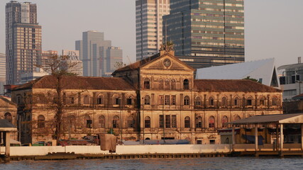Fototapeta premium January 2 2021 - Bangkok, Thailand : Beautiful Old Customs House at Chao praya River and high modern building as background