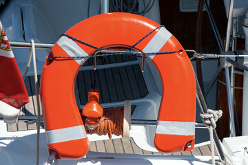 Close-up of an orange and white life belt and emergency light for localization on a yacht.