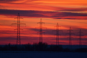 High voltage poles photographed at a beautiful sunset. Red background.