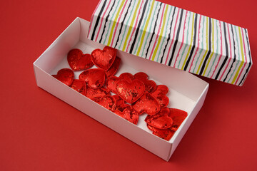red decorative hearts in paper box on red background