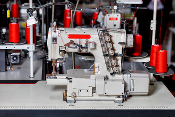 Modern sewing equipment, multifunctional sewing machine with spools of red thread close-up.