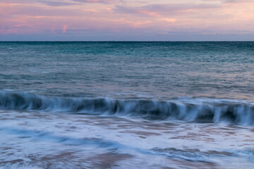 Fototapeta na wymiar beautiful blue sea with waves, beach with rocks, sky at sunset