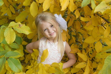 happy cute little beautiful girl in yellow autumn foliage