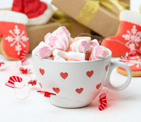 white ceramic cup with cocoa and marshmallows, behind a gift box and a Christmas toy