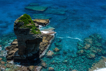 Cliff view of a famous Tategami stone surrounded by coral reefs and an impressive transparent blue...