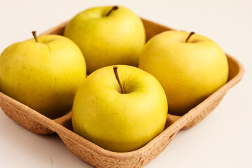 Naklejka na ściany i meble Close up of fresh yellow apples on biodegradable pulp paper food tray isolated on white. Recyclable packagingбsustainable consumption concept.