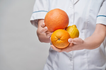 nutritionist doctor healthy lifestyle concept - holding fresh organic citrus fruits - grapefruit,...
