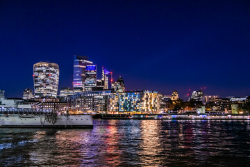 Fototapeta na wymiar London cityscape at night view at the City of London from across the river Thames, night life in UK capital city, lots of lights and reflections in the water and beautiful sky