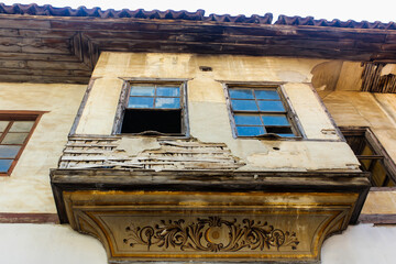 Fototapeta na wymiar View od ruins of a historic house from below in Old Town, Antalya, Turkey. Beautiful exterior design and broken windows of an abondoned house and art work under the window.