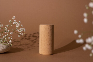 Wooden cylinders and flowers the brown pastel background.Good as shape geometrical podiums for showing products.