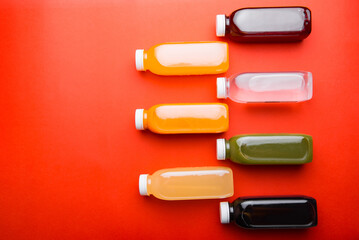 Photo of many detox juice bottles over red background with copyspace.