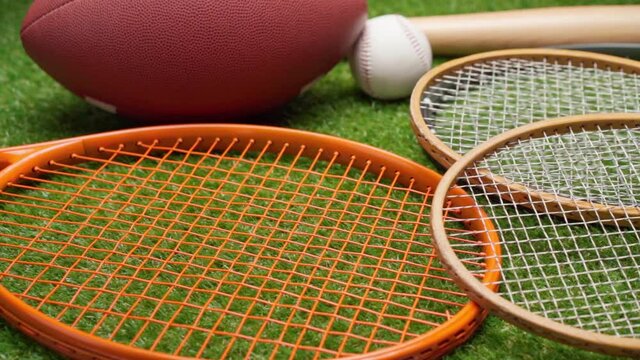 Sport equipment; rackets, balls and baseball bat on grass