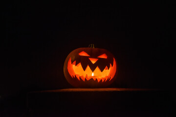 Scary halloween pumpkin with candle light inside, put on black background