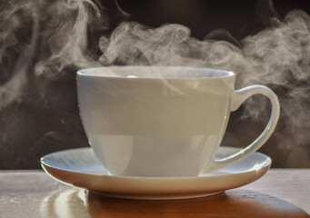 Hot tea cup on a frosty winter day put on wooden table with background of front garden in morning.