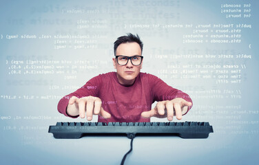 Portrait of a man in glasses and a red T-shirt who types on the keyboard and looks at the monitor...
